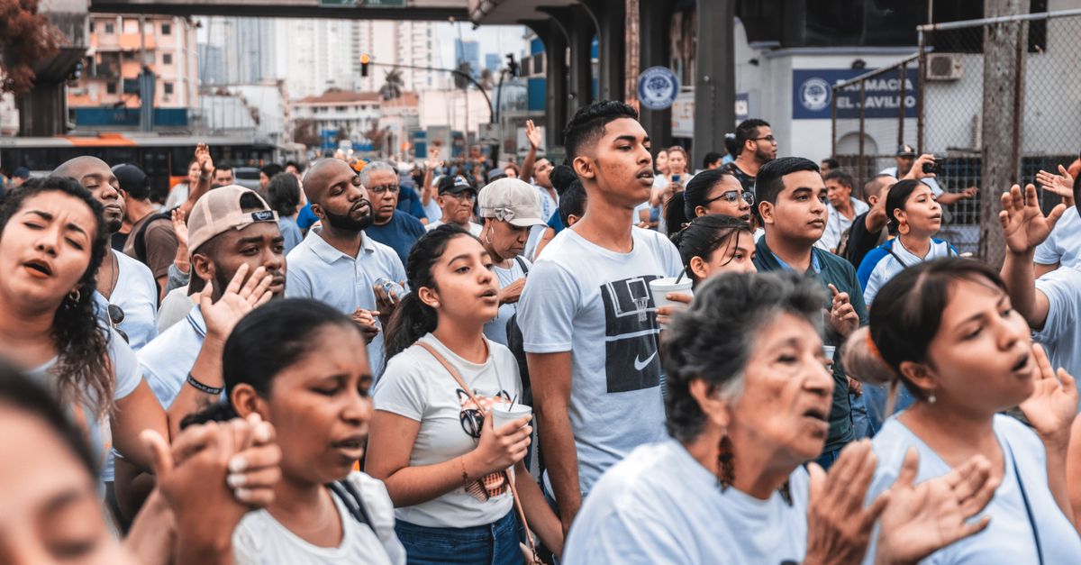 A large group of diverse people gathered outdoors, engaging in a community event in an urban setting.